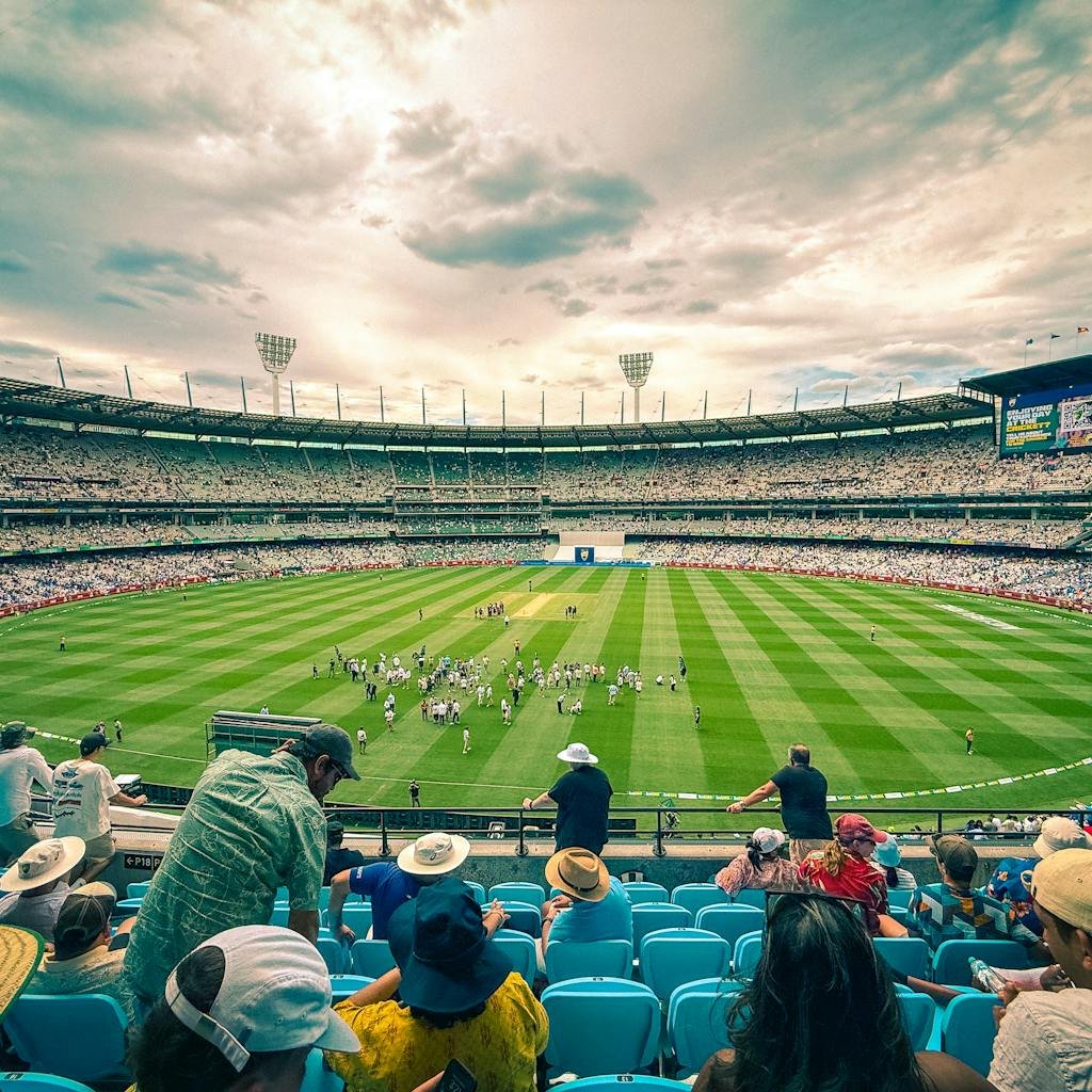 A lively cricket match at Melbourne Cricket Ground with a colorful crowd under a dynamic sky.